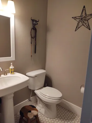 Pedestal sink with brushed nickel faucet, ceramic toilet, and hexagonal tile flooring