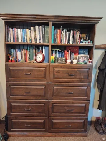 Built-in wood-finish cabinetry featuring open shelving and multiple storage drawers with dark hardware