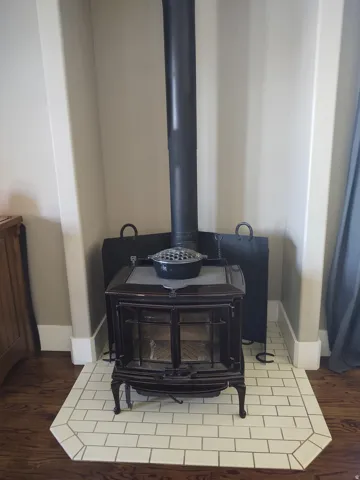 Cast iron wood-burning stove set on a subway tile hearth with dark grout