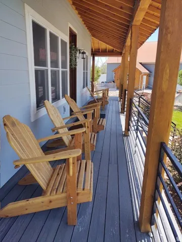 Expansive covered porch featuring a wood-plank ceiling, exposed wood beams, composite decking, and horizontal metal railings