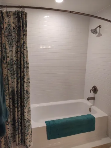 White subway tile surround, recessed lighting, and bronze-finish fixtures