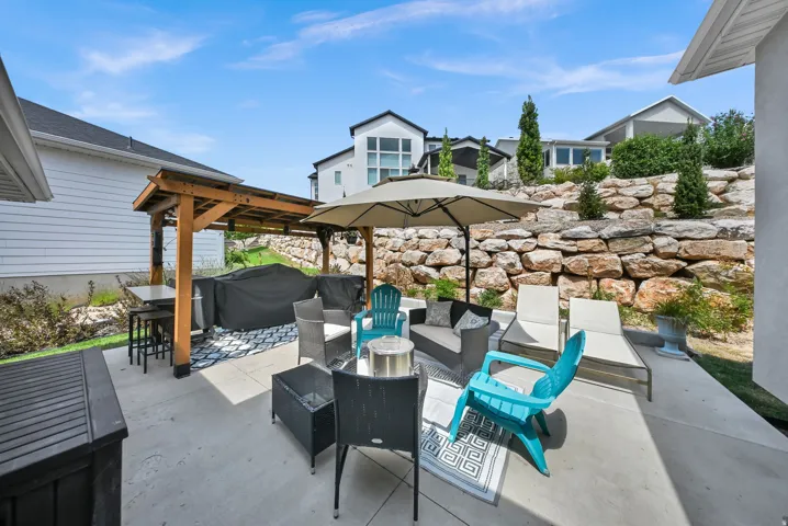 Concrete patio featuring a wood pergola and a stone retaining wall