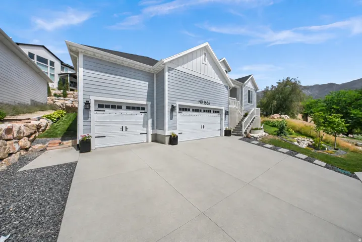 Two-car garage with panel-style doors, concrete driveway, and stone retaining walls