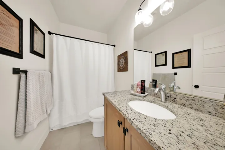 Vanity with stone countertop, undermount sink, and wood-finish cabinetry