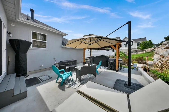 Expansive concrete patio featuring an overhead umbrella and a pergola structure