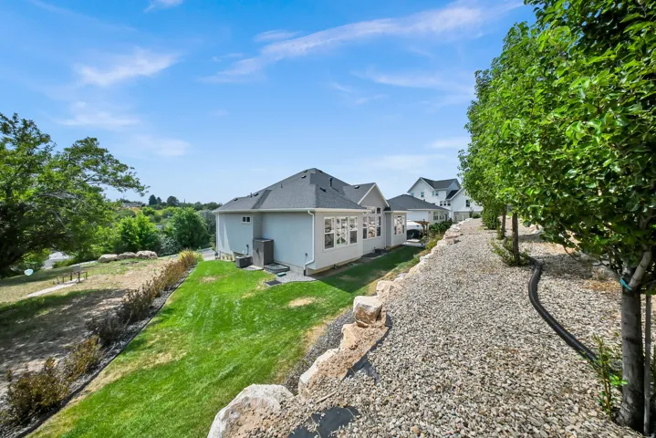 Expansive backyard featuring a manicured lawn, established trees, and a gravel path