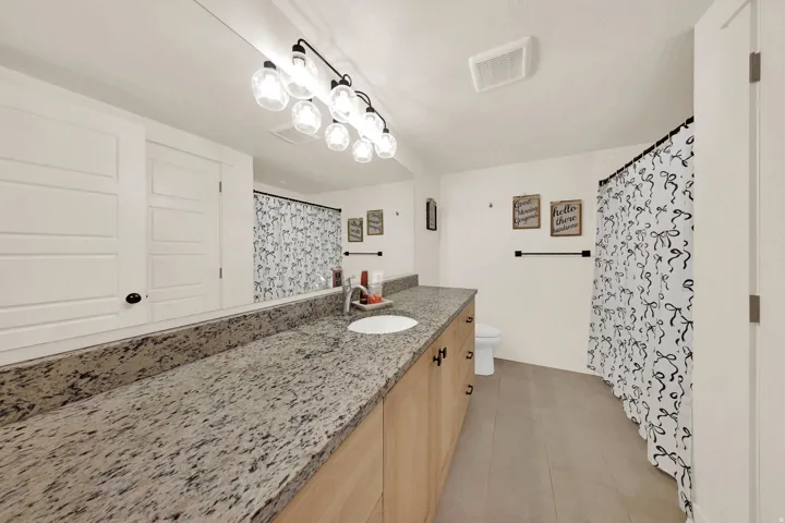 Expansive vanity featuring a light-toned countertop, wood-finish cabinetry, and a circular undermount sink