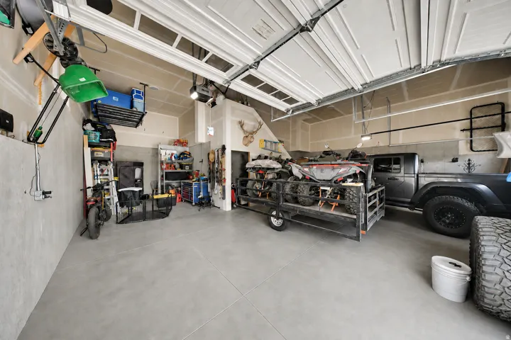 Spacious garage featuring a smooth concrete floor, white panel garage door, and ample wall space