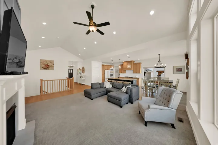 Vaulted ceilings with recessed lighting, an electric fireplace, wood-finish flooring, and expansive windows