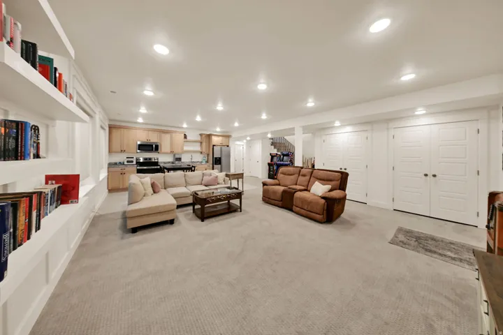Spacious living area with recessed lighting, integrated shelving, and light-toned carpeting