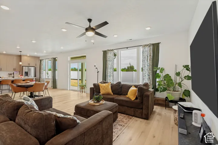 Open-concept living space with light wood-finish flooring, recessed lighting, and a ceiling fan