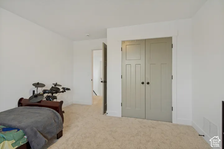 Neutral-toned carpeting paired with white walls, featuring a paneled bi-fold closet door with matte black hardware and a solid interior door