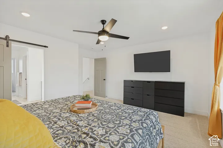 Ceiling fan with integrated lighting, recessed lighting, barn-style sliding door, light-toned carpeting, and a wall-mounted television