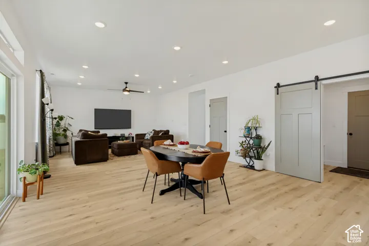 Bright open-concept living space with wood-finish flooring, recessed lighting, and a contemporary barn door