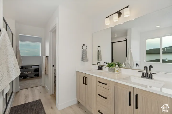 Dual vanity with integrated sinks, light wood-finish cabinetry, and black fixtures