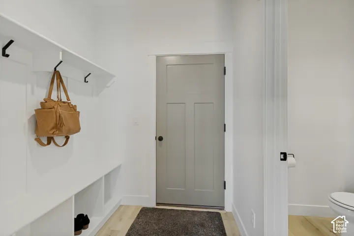 Built-in storage bench with cubbies, white wall paneling, and black wall hooks