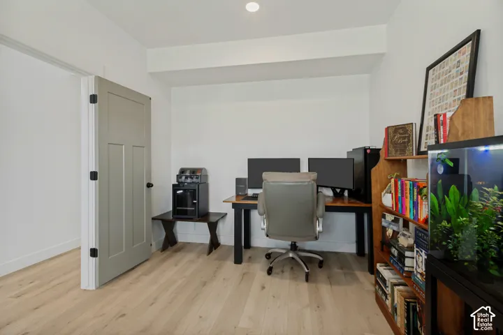 Light wood-finish flooring, white walls, and a light-colored door with black hardware