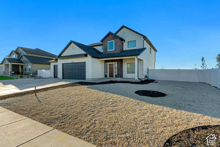 Contemporary two-story exterior with vertical siding and stone accents, a dark garage door, and a covered entry