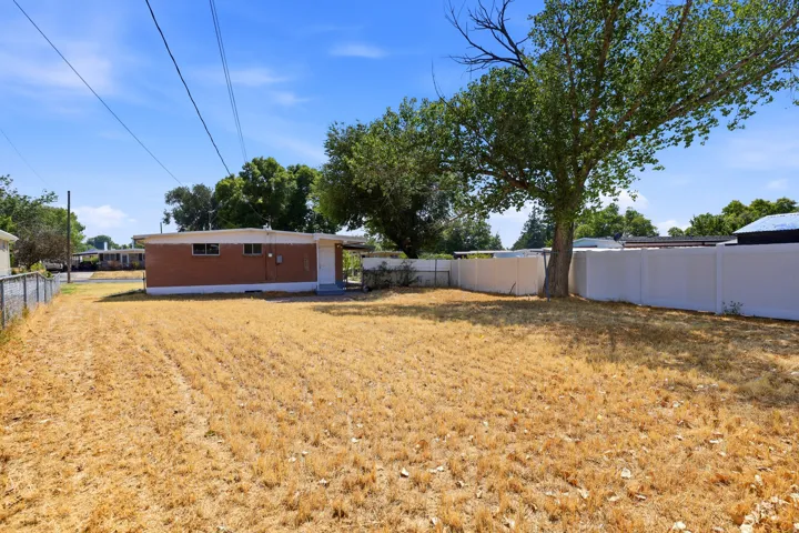 Backyard featuring a generous lot with mature shade trees, landscaping, and fencing