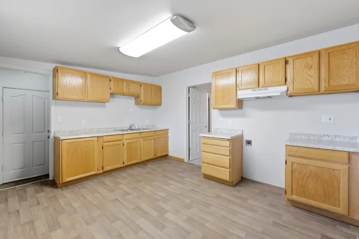 Kitchen featuring extensive wood cabinetry, light-toned countertops, and wood-finish flooring