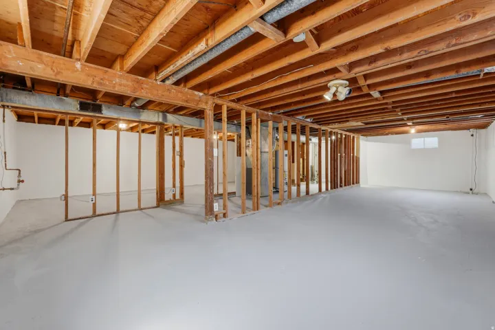 Unfinished basement featuring exposed wood joists and structural framing