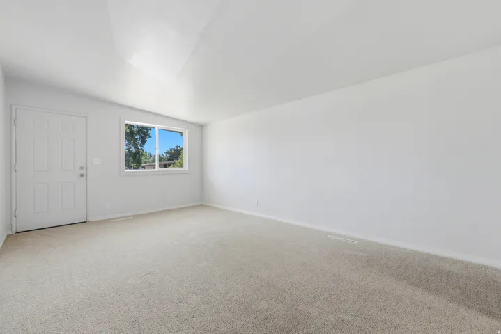 Spacious room featuring  light-colored carpeting, and a window with exterior visibility