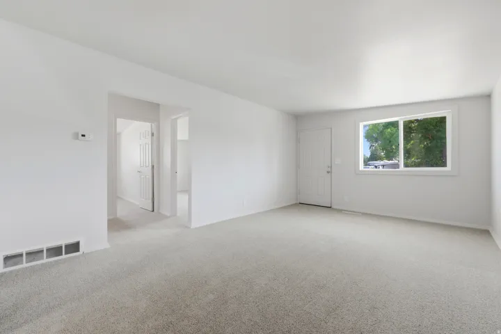 Open concept living area featuring light-colored carpeting and white walls