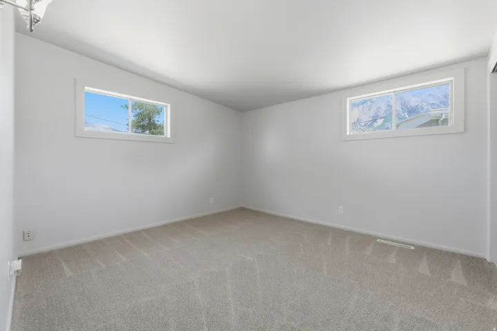 Bedroom 3 featuring clean white walls, neutral carpeting, and dual windows with natural light