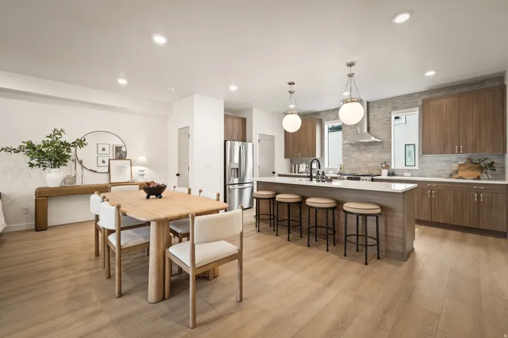 Open concept living area featuring wood-finish flooring, a kitchen island with seating, stainless steel appliances, and wood-finish cabinetry