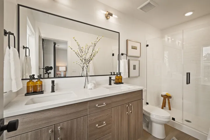 Dual sink vanity with wood-finish cabinetry, white countertop, and rectangular undermount sinks