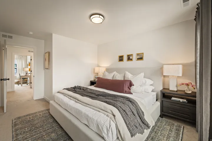 Recessed ceiling light, carpeted flooring, white walls, textured headboard, dark wood-finish nightstands
