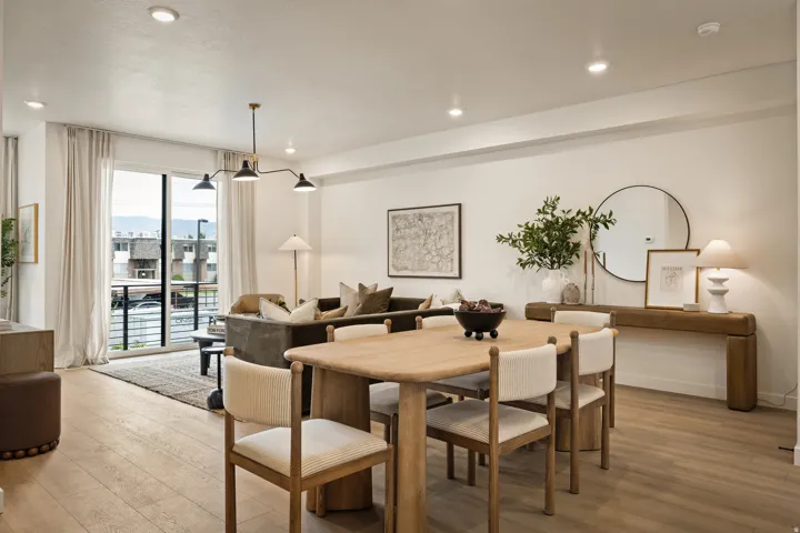 Recessed ceiling lighting, wood-finish flooring, full-height sliding glass doors, and a linear chandelier with three fixtures