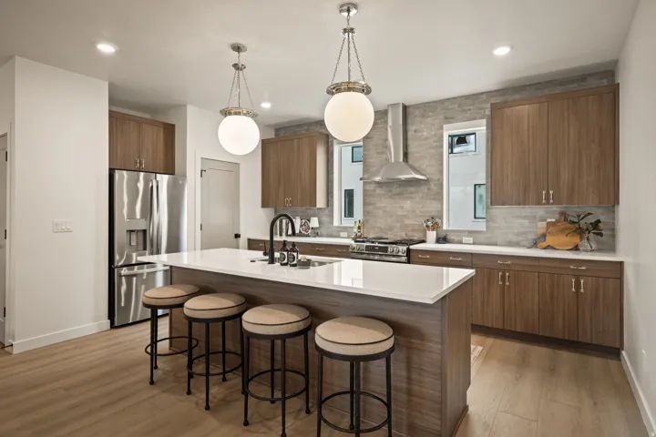 Kitchen featuring wood-finish cabinetry, stainless steel appliances, a center island with a white countertop, and pendant lighting
