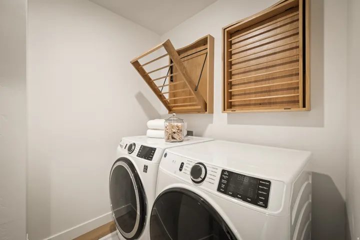 White front-loading washer and dryer with wall-mounted wood-finish drying racks