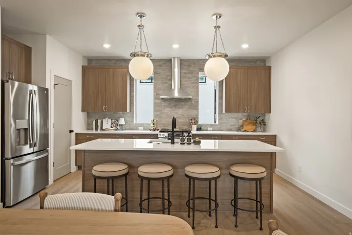 Kitchen featuring wood-finish cabinetry, stainless steel appliances, a center island with countertop seating, and two pendant light fixtures