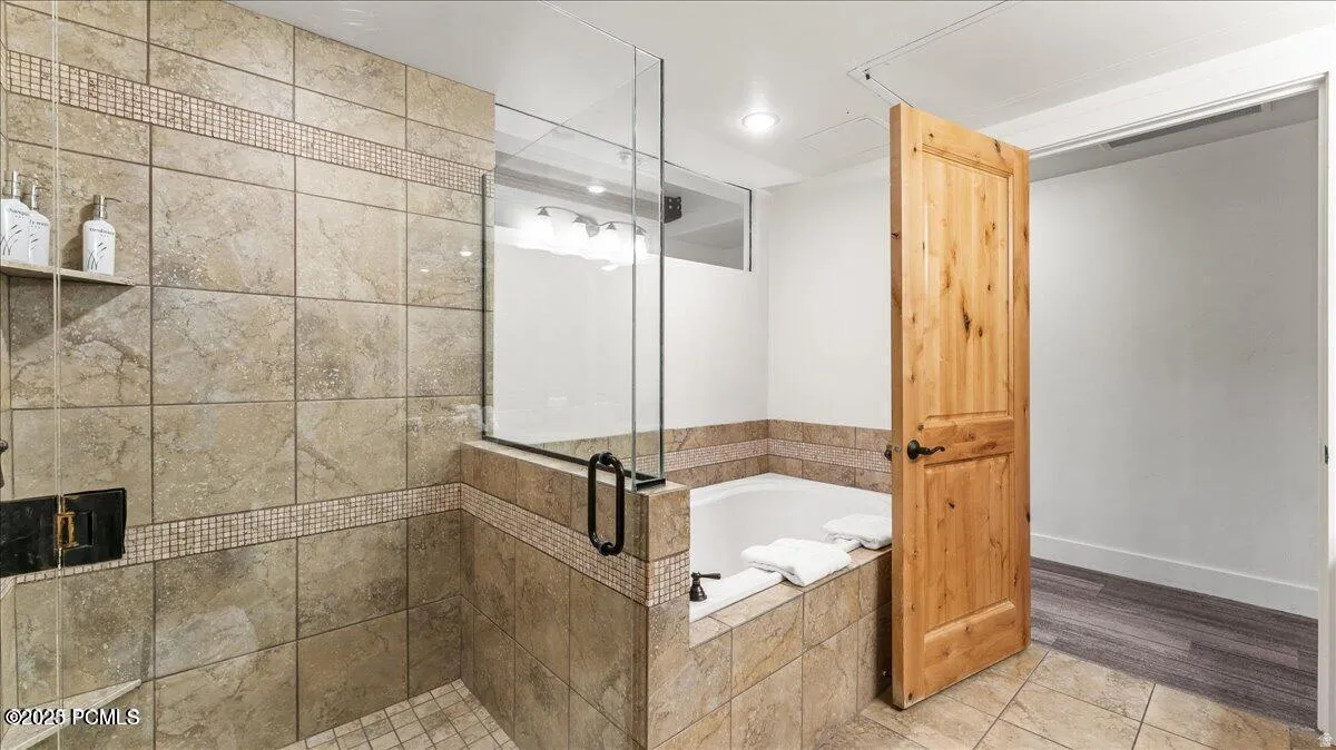 Tiled shower with glass enclosure, mosaic accent band, and built-in niche