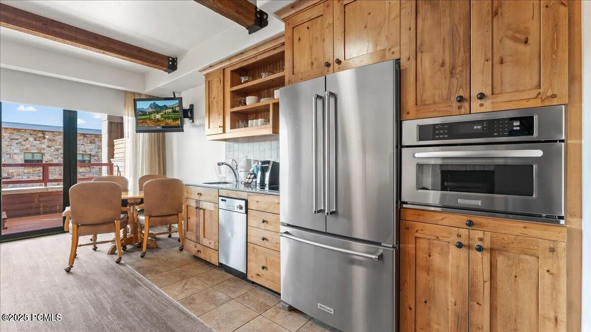 Wood-finish cabinetry paired with stainless steel appliances, including a built-in microwave and French door refrigerator