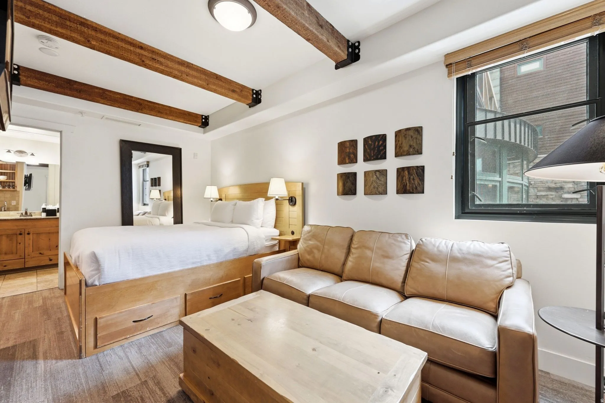 Exposed wood beams, wood-finish flooring, and a built-in bed frame with storage drawers