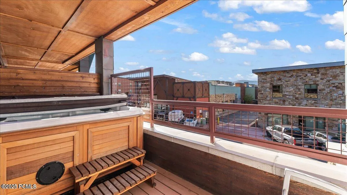 Covered outdoor deck with built-in spa, wood-finish paneling, and metal railings