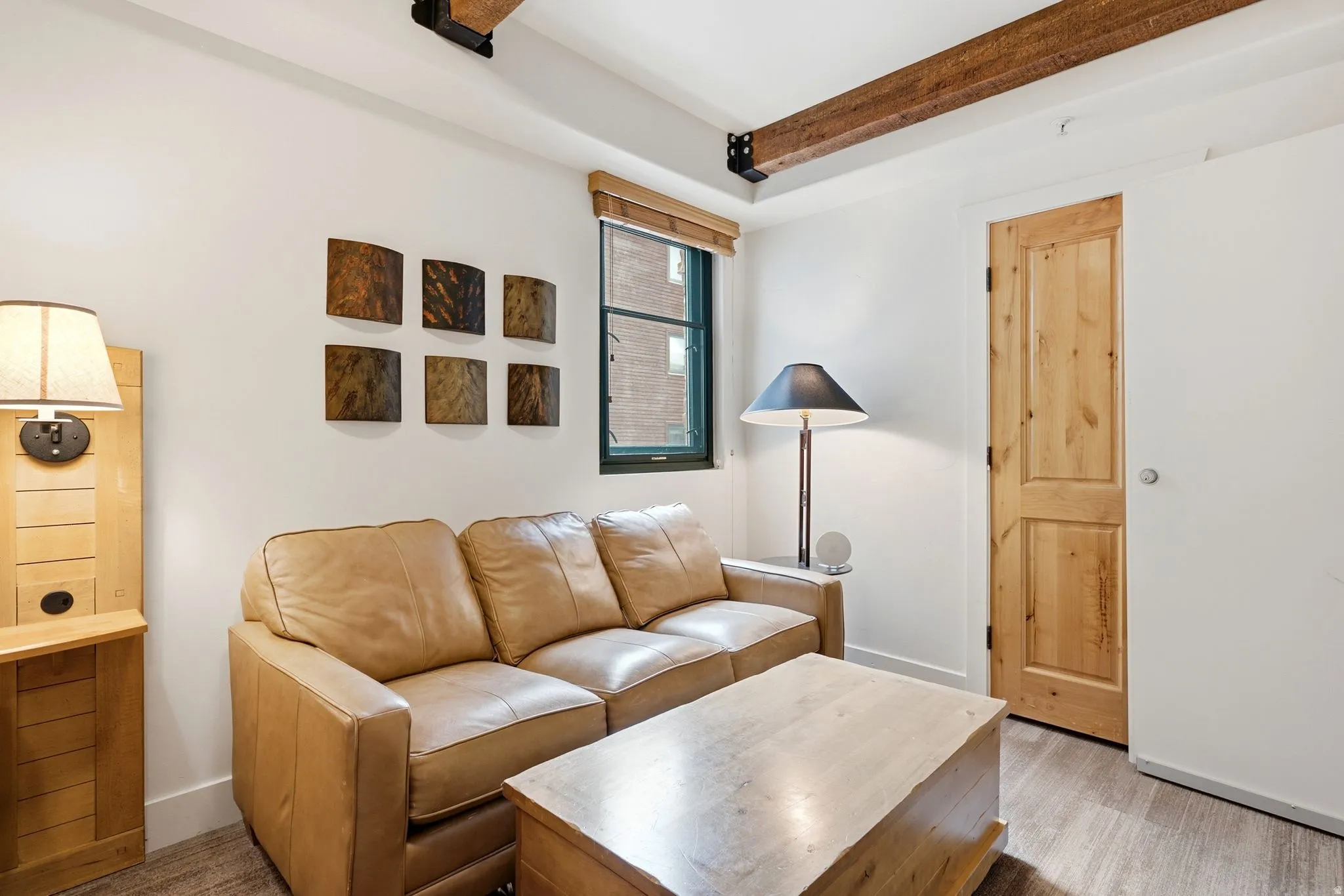 Exposed wood beam ceiling, wood-finish flooring, wood door, and a built-in wood cabinet