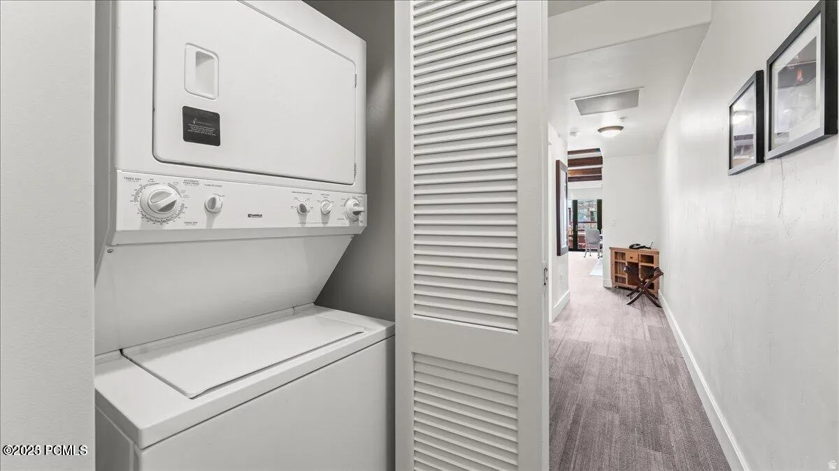 Stackable washer and dryer unit, louvered bi-fold closet doors, and wood-finish flooring