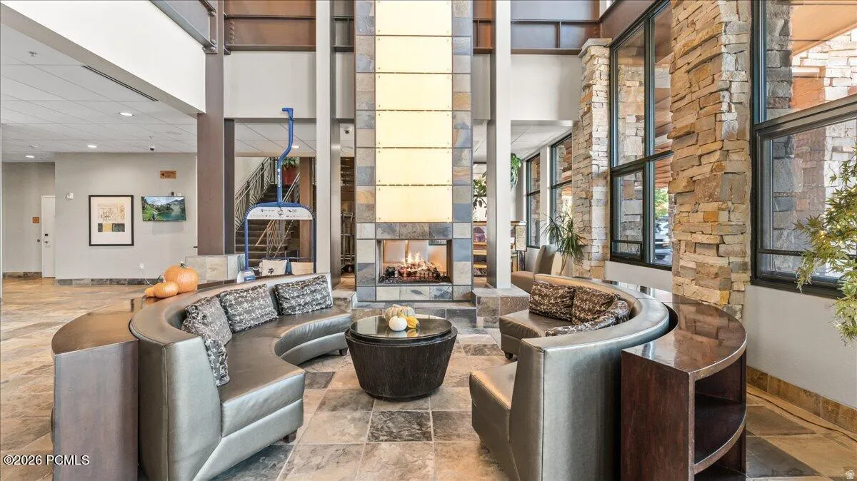 Two-story interior with a stone fireplace, large format stone tile flooring, and extensive window walls