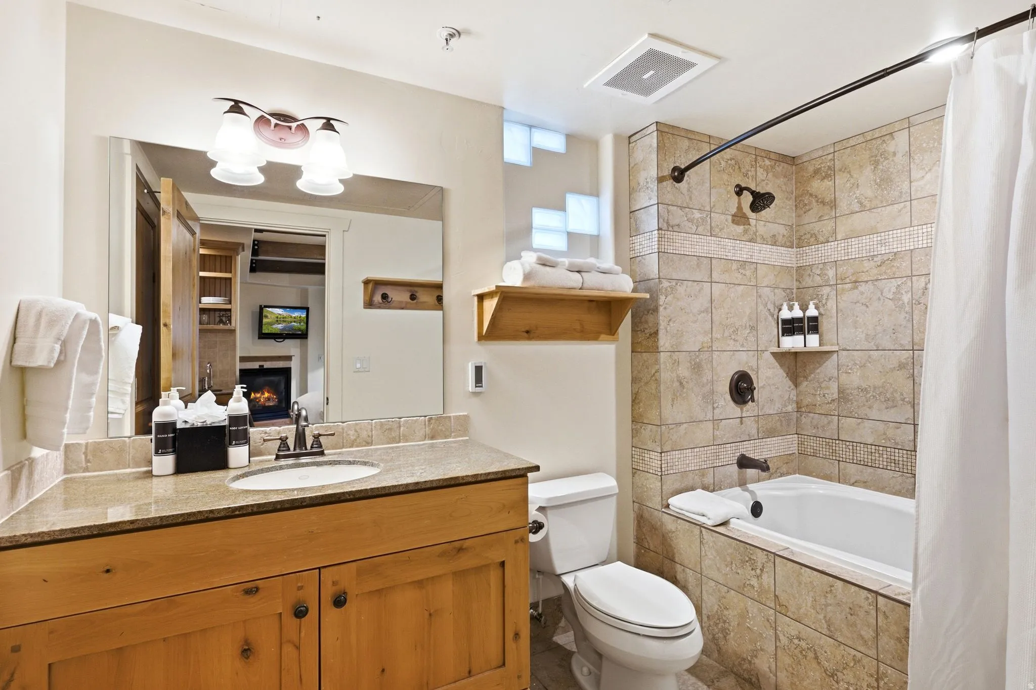 Bathroom featuring a wood-finish vanity with an undermount sink, a light-toned countertop, and a tiled tub/shower combination
