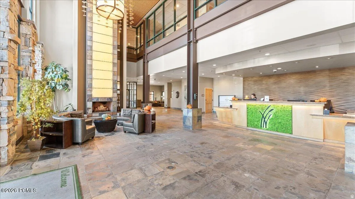 Spacious lobby featuring stone-clad walls, a large fireplace, and a light wood reception desk