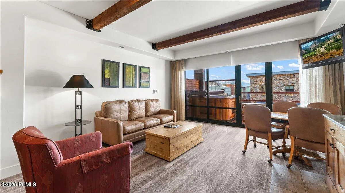 Wood-finish flooring throughout, exposed ceiling beams, built-in hot tub on a private balcony, and a dining area with a built-in cabinet