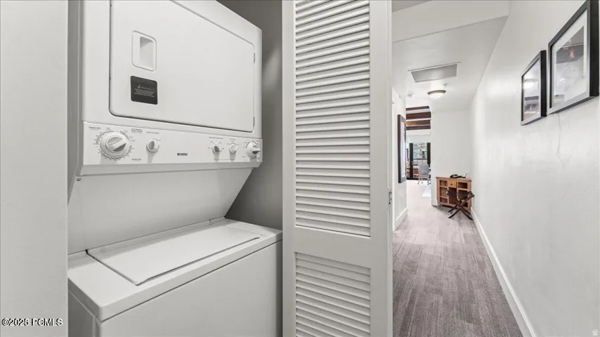 Stackable washer and dryer unit, louvered bi-fold closet doors, and wood-finish flooring