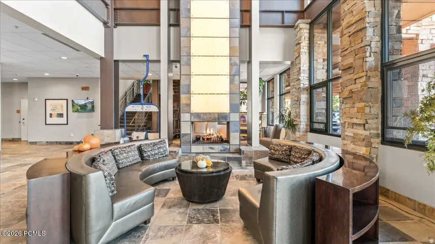 Two-story interior with a stone fireplace, large format stone tile flooring, and extensive window walls