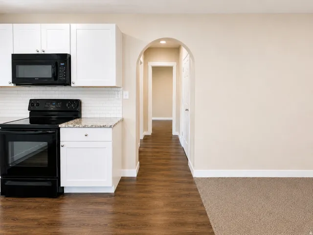 Kitchen featuring white cabinetry, subway tile backsplash, black appliances, and speckled countertop