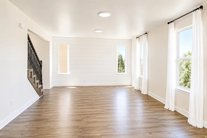 Wood-finish flooring, recessed ceiling lights, multiple windows, and a staircase with wrought iron balusters