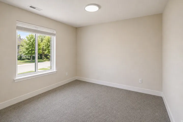 Neutral-toned walls, grey carpeting, and a flush-mount ceiling light